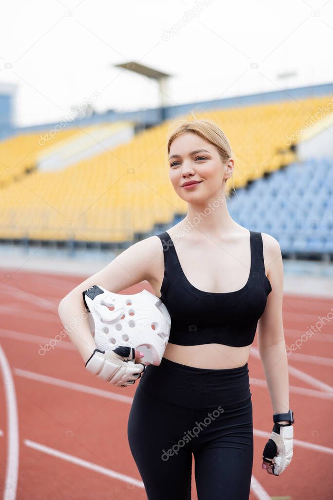 cheerful woman with sports helmet looking away on stadium