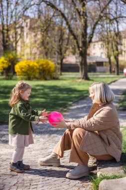 side view of happy mother and daughter playing with ball in city park