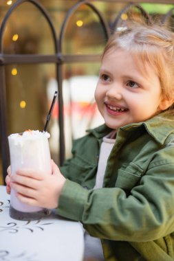 Neşeli kız elinde bir bardak lezzetli milkshake tutuyor.