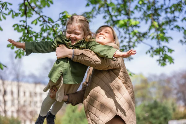 low angle view of happy woman holding cheerful daughter outdoors