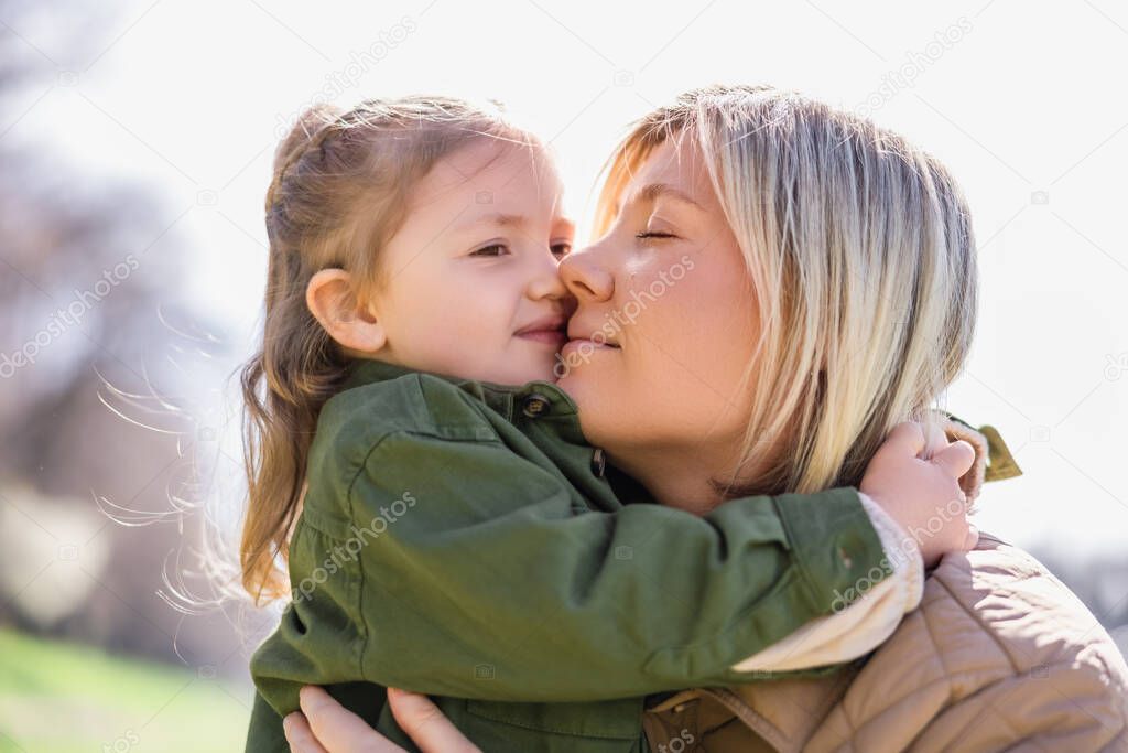 happy mom and daughter embracing outdoors