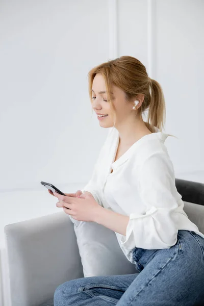 Jovem Mulher Positiva Fone Ouvido Usando Smartphone Sala Estar — Fotografia de Stock