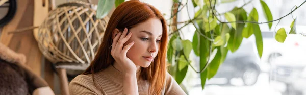 Young redhead woman holding hand near cheek in cafe, banner — Stock Photo