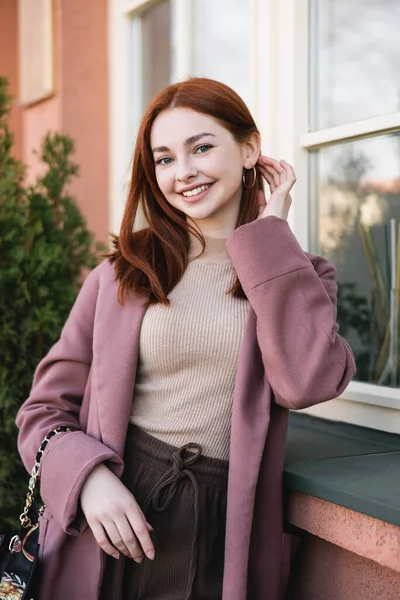 Junge fröhliche Frau mit roten Haaren in der Nähe des Gebäudes — Stockfoto