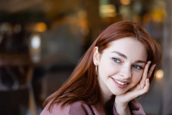 Portrait de jeune femme heureuse aux cheveux roux regardant ailleurs — Photo de stock