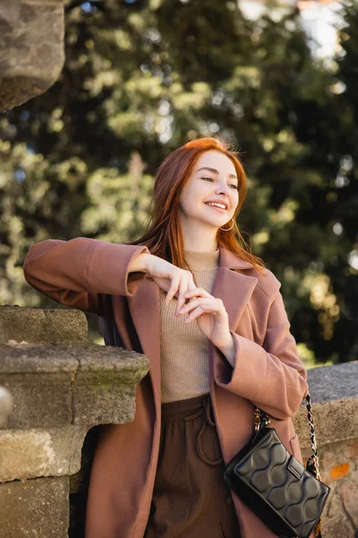 Portrait de femme rousse heureuse en manteau regardant loin à l'extérieur — Photo de stock