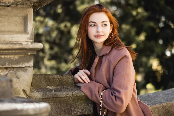Portrait of young redhead woman in coat looking away outside — Stock Photo