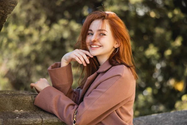 Portrait of positive redhead woman in coat posing outside — Stock Photo