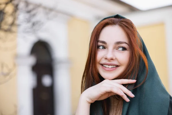 Retrato de jovem mulher satisfeita em lenço de cabeça sorrindo enquanto olha para longe — Fotografia de Stock