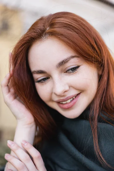 Portrait of young redhead woman in headscarf smiling while looking down — стоковое фото