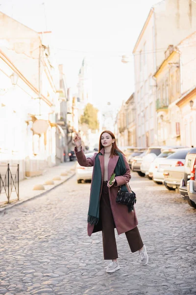 Comprimento total da mulher ruiva chamando táxi na rua europeia — Fotografia de Stock