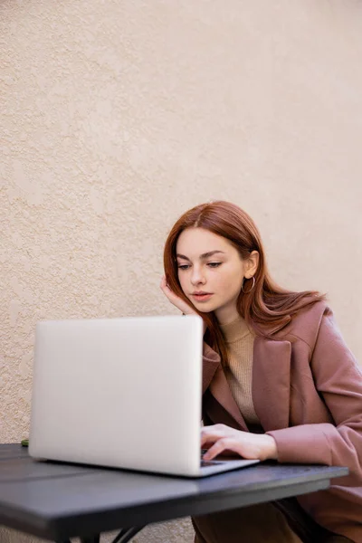 Jovem mulher bonita com cabelo vermelho usando laptop fora — Fotografia de Stock