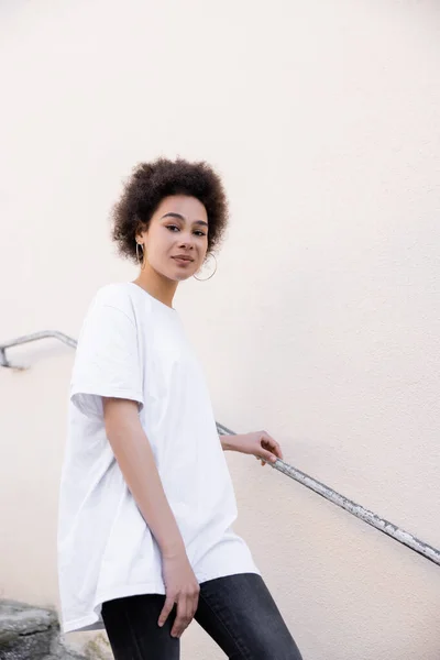 Curly african american woman walking near rusty handrail — Stock Photo