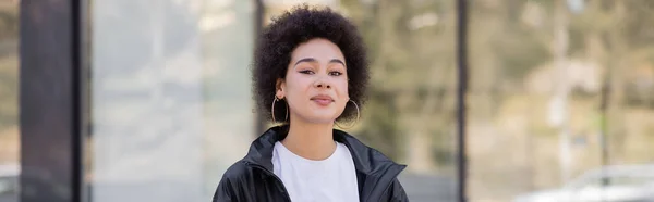 Молода афроамериканська жінка в куртці дивиться на фотоапарат, банер — стокове фото