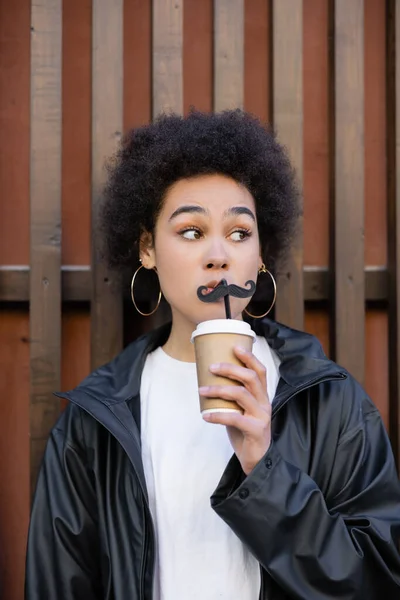 Young african american woman holding paper cup and straw with moustache — Stock Photo