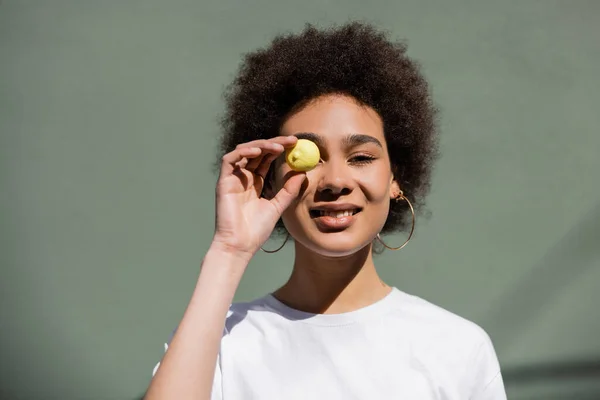 Glücklich afrikanisch-amerikanische Frau bedeckt Auge mit gelben Bonbons — Stockfoto