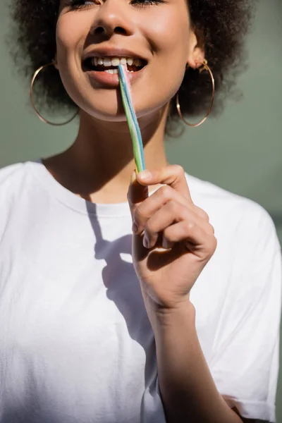 Cropped view of pleased african american woman eating jelly straw - foto de stock