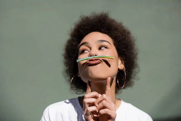 Young african american woman holding jelly straw with mouth while grimacing outside — Stock Photo