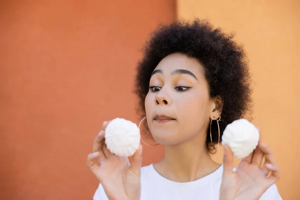 Curious african american woman holding zefir near orange wall — Stock Photo