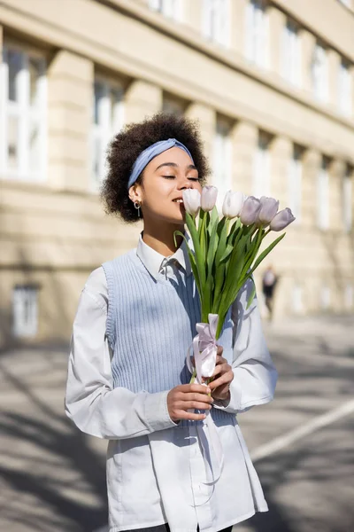 Joyful african american woman looking at tulips on street — Foto stock