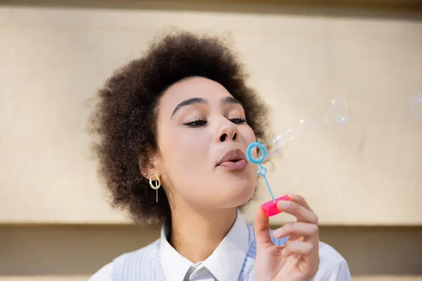 Joven mujer afroamericana soplando burbujas de jabón - foto de stock