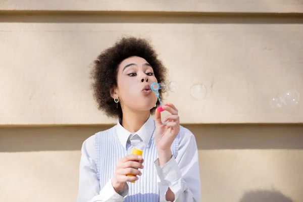 Curly african american woman blowing soap bubbles - foto de stock