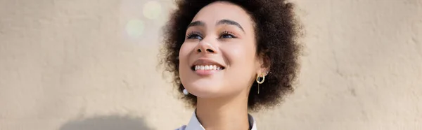 Encaracolado afro-americano mulher sorrindo enquanto olha para longe, banner — Fotografia de Stock