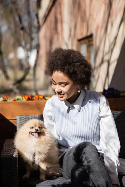 Happy african american woman looking at pomeranian spitz — Stock Photo