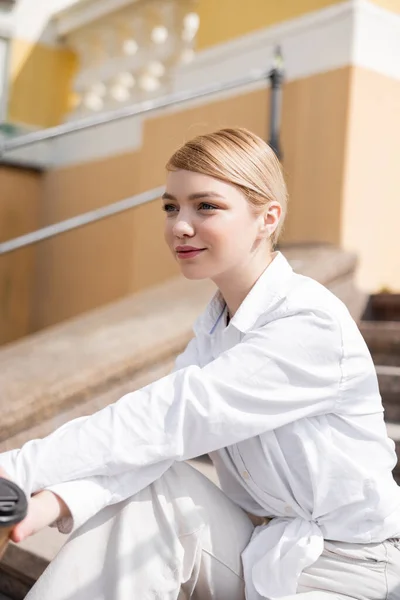 Junge blonde Frau lächelt, während sie draußen wegschaut — Stockfoto