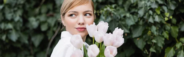 Bonita mujer joven con tulipanes mirando al aire libre, pancarta - foto de stock