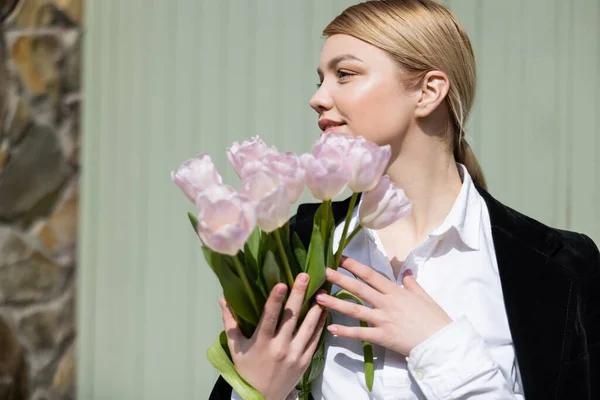 Jeune femme avec des tulipes blanches fraîches regardant loin — Photo de stock