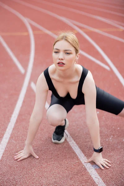 Bonita mujer joven en ropa deportiva negro ejercitando en el estadio - foto de stock