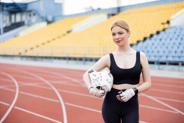 Smiling woman in sportswear holding sports helmet and looking away — стоковое фото