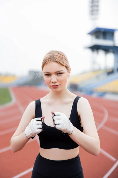 Femme de sport en soutien-gorge de sport et gants de fitness s'entraînant sur le stade — Photo de stock