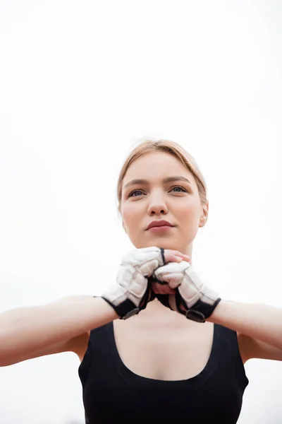 Low angle view of blonde sportswoman in fitness gloves warming up outdoors — Stock Photo