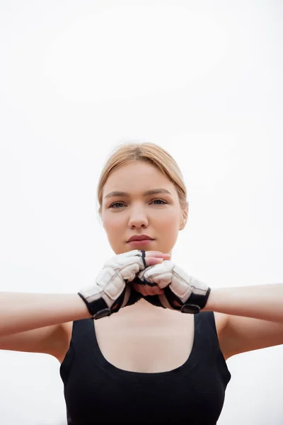 Vista de ángulo bajo de la mujer joven calentando en guantes de fitness al aire libre - foto de stock