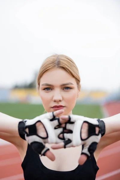 Jeune sportive en gants de fitness s'échauffant au premier plan flou — Photo de stock