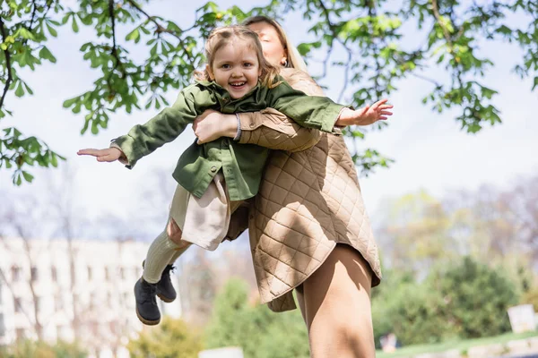 Low angle view of woman holding happy girl while playing outdoors — Stock Photo