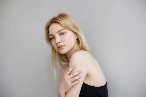 Blonde woman looking at camera isolated on grey — Stock Photo