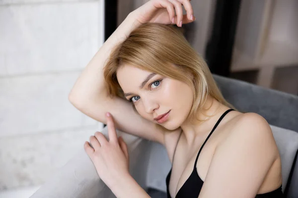 Portrait of young blonde woman looking at camera on couch — Stock Photo