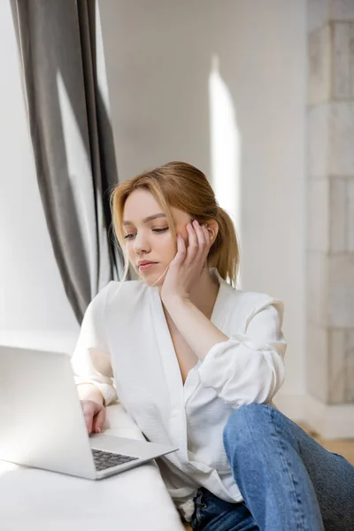 Freelancer loira usando laptop borrado em casa — Fotografia de Stock