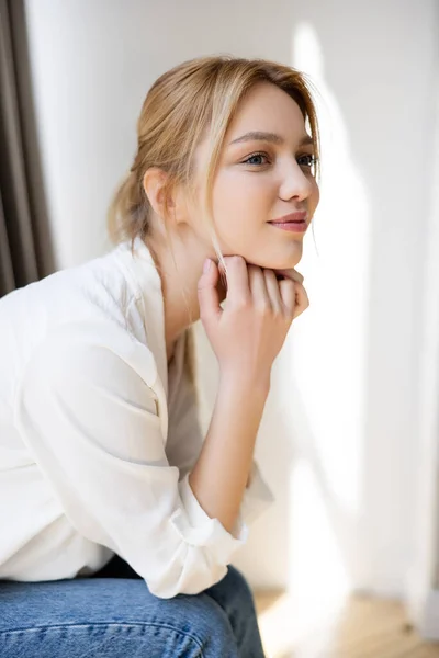 Jolie jeune femme en chemisier regardant loin à la maison — Photo de stock