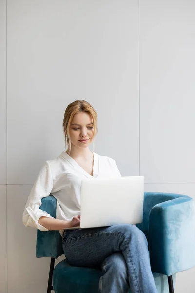 Giovane freelance utilizzando il computer portatile sulla poltrona a casa — Foto stock