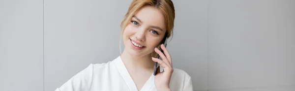 Positive blonde woman talking on mobile phone at home, banner — Stock Photo