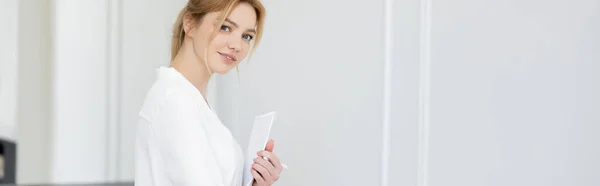 Hübsche blonde Frau in Bluse hält Notizbuch zu Hause, Banner — Stockfoto