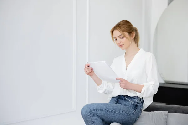 Junge Frau in Bluse hält Notizbuch auf Couch zu Hause — Stockfoto