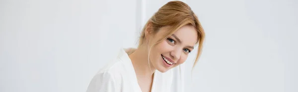 Joven mujer alegre en blusa blanca mirando a la cámara en casa, pancarta - foto de stock