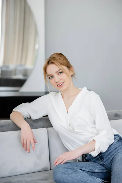 Portrait de femme blonde souriante assise sur le canapé — Photo de stock