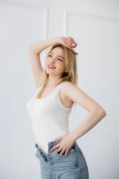 Красивая блондинка в джинсах и боди-костюме стоит в гостиной — стоковое фото