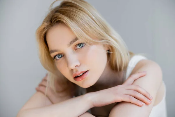 Portrait de jeune femme blonde regardant la caméra isolée sur gris — Photo de stock